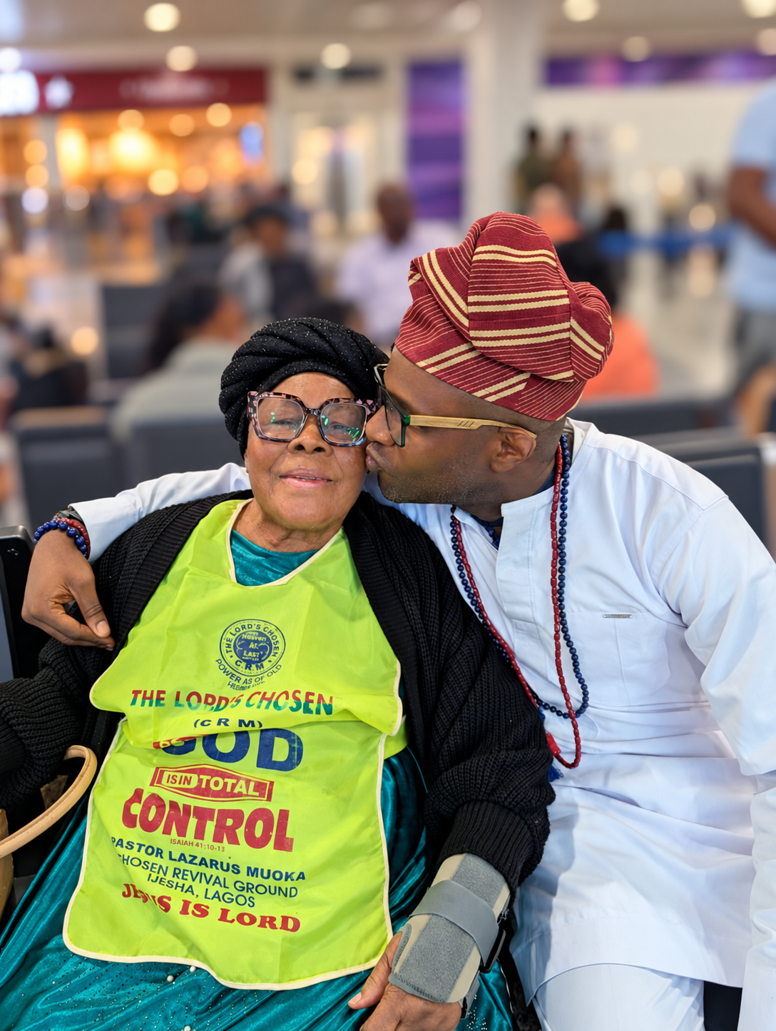 Lékan kissing his mum Betty Nnenna Nwakaego on the cheek at Heathrow, with the airport background blurred