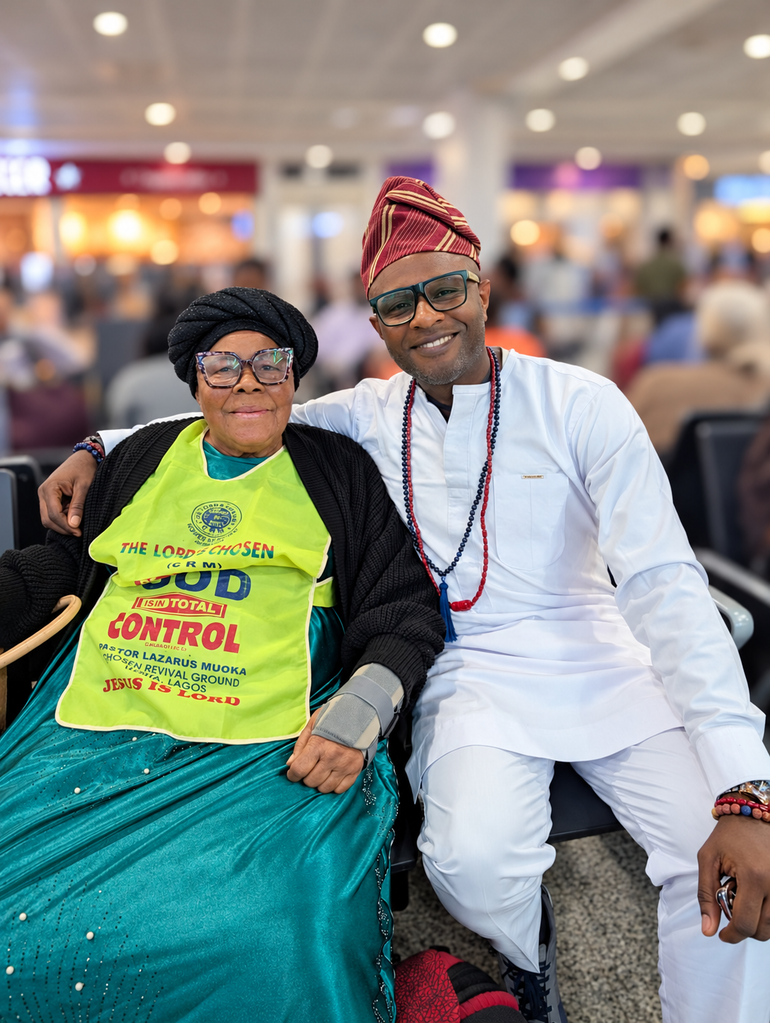 Betty Nnenna Nwakaego and Lékan smiling together at Heathrow, with the busy terminal softly blurred